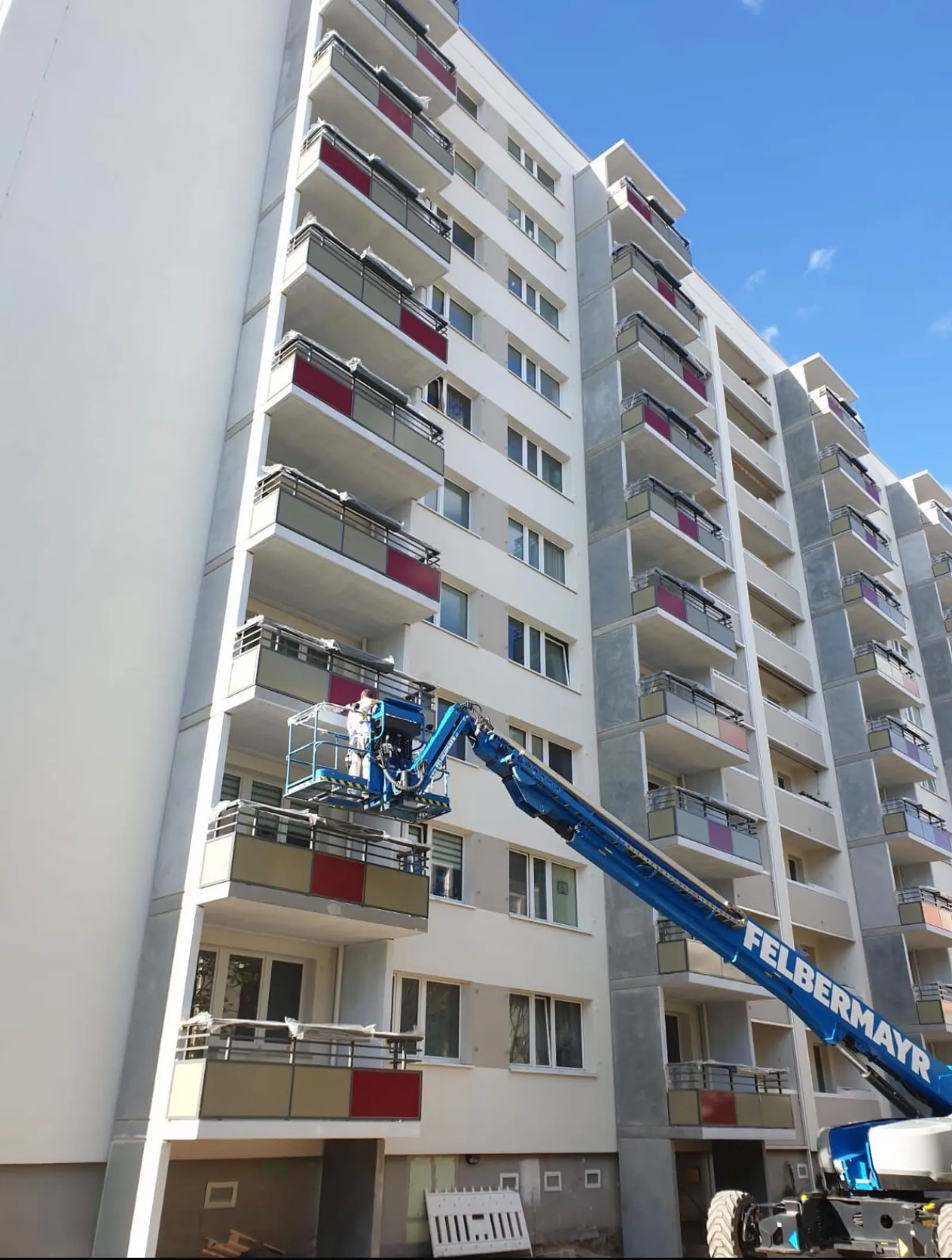 Arbeitsbühne im Einsatz an einer Balkonreihe eines Wohngebäudes