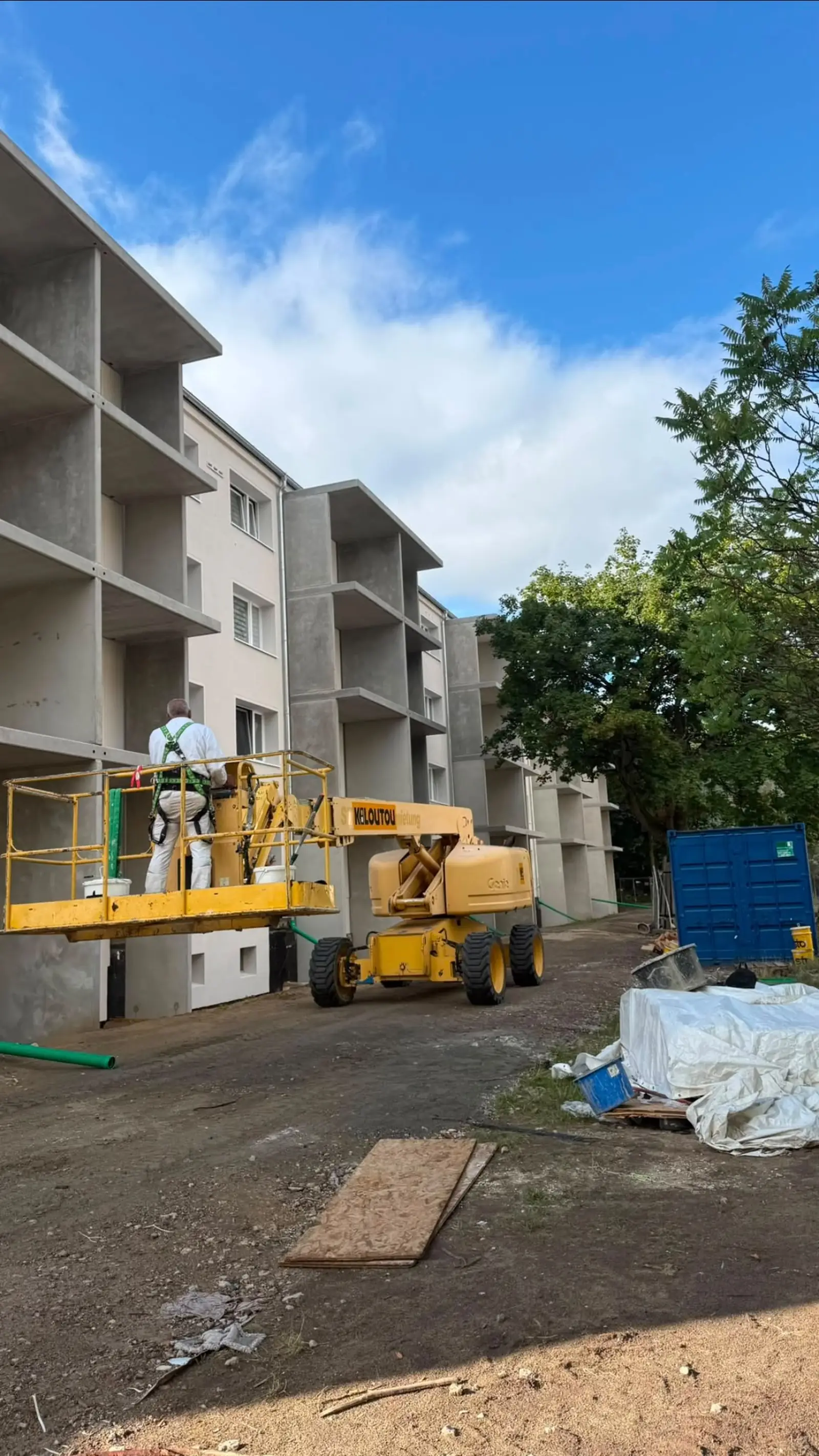 Mitarbeiter im Korb einer Arbeitsbühne bei Arbeiten an der Fassade